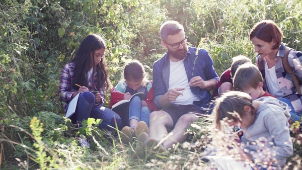 A group of small school children with teacher on field trip in nature. Slow motion.