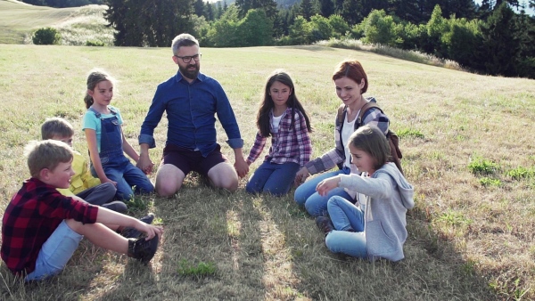 Group of school children with teacher on field trip in nature, sitting in circle. Slow motion.