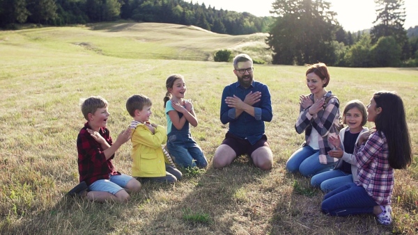 Group of school children with teacher on field trip in nature, sitting in circle. Slow motion.