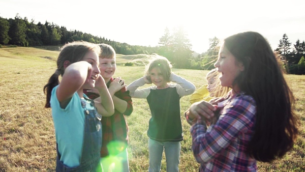 Portrait of group of school children standing on field trip in nature, playing. Slow motion.