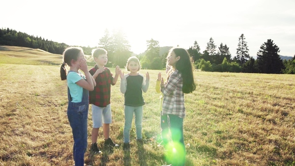 Portrait of group of school children standing on field trip in nature, playing. Slow motion.