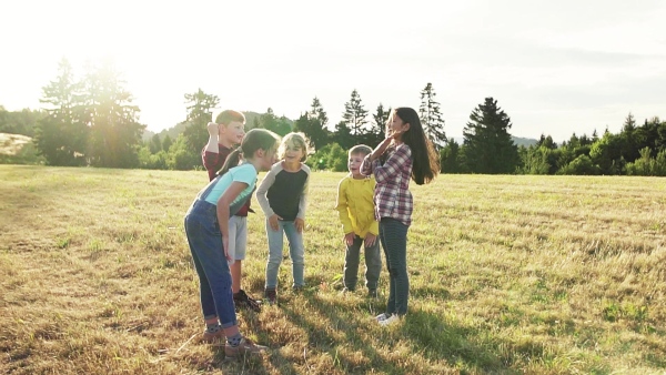 Portrait of group of school children standing on field trip in nature, playing. Slow motion.