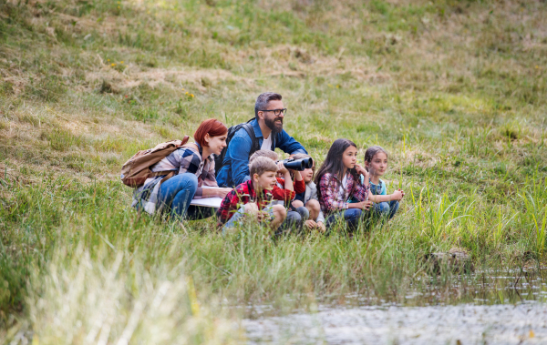 A group of small school children with teacher on field trip in nature.