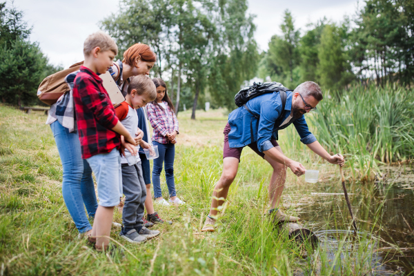 A group of small school children with teacher on field trip in nature.