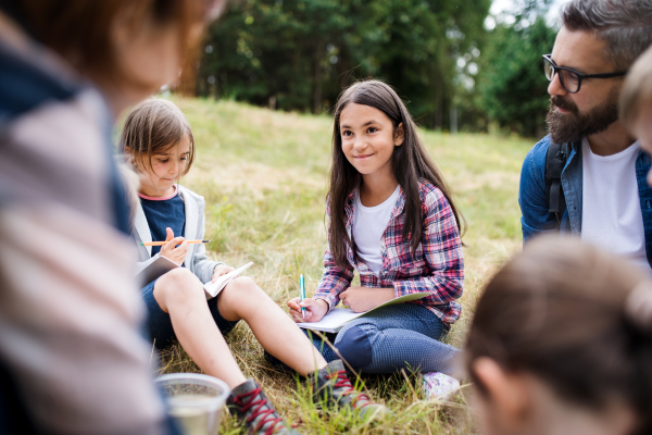 A group of small school children with teacher on field trip in nature, learning science.