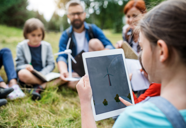 A group of school children with teacher and windmill model on field trip in nature.