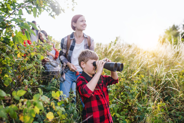 A group of school children with teacher on field trip in nature, using binoculars.