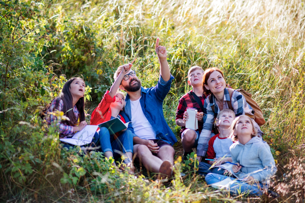 A group of small school children with teacher on field trip in nature.