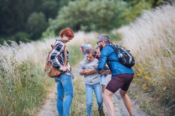 A group of small school children with teacher on field trip in nature, running.