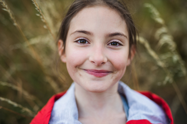 Portrait of school child standing on field trip in nature, looking at camera.