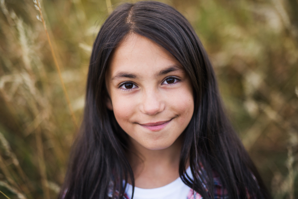 Portrait of school child standing on field trip in nature, looking at camera.