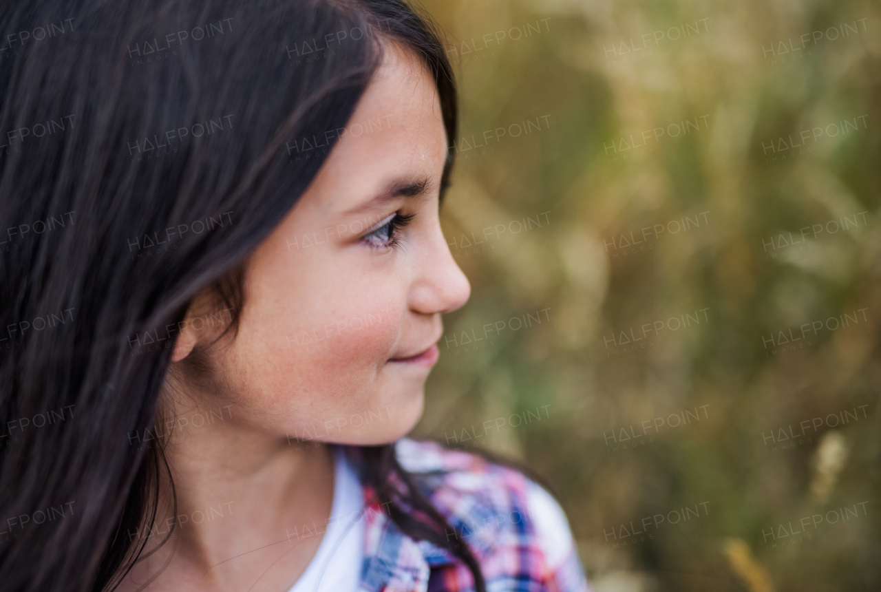 A side view of school child standing on field trip in nature, headshot. Copy space.