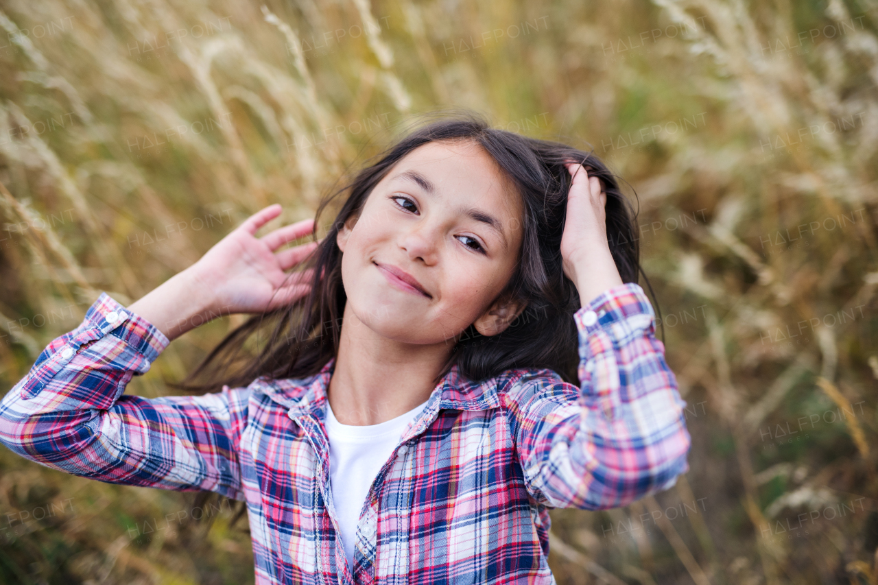 Portrait of school child standing on field trip in nature, looking at camera.