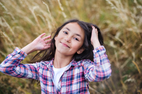 Portrait of school child standing on field trip in nature, looking at camera.