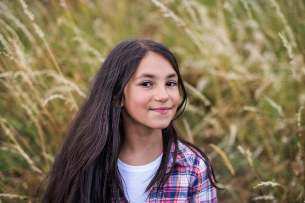 Portrait of school child standing on field trip in nature, looking at camera.