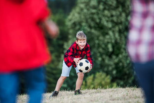 Portrait of group of school children standing on field trip in nature, playing with a ball.