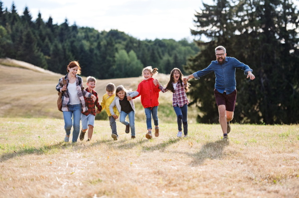 A group of small school children with teacher on field trip in nature, running.