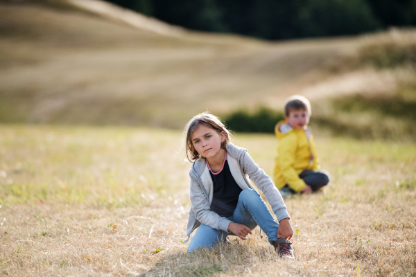 School children sitting on the ground on a field trip in nature, looking at camera.