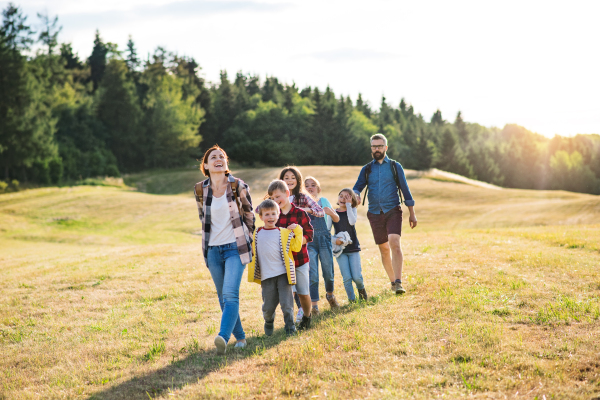 A group of small school children with teacher on field trip in nature, walking.