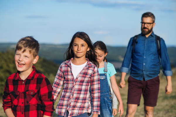 A group of small school children with teacher on field trip in nature, walking.