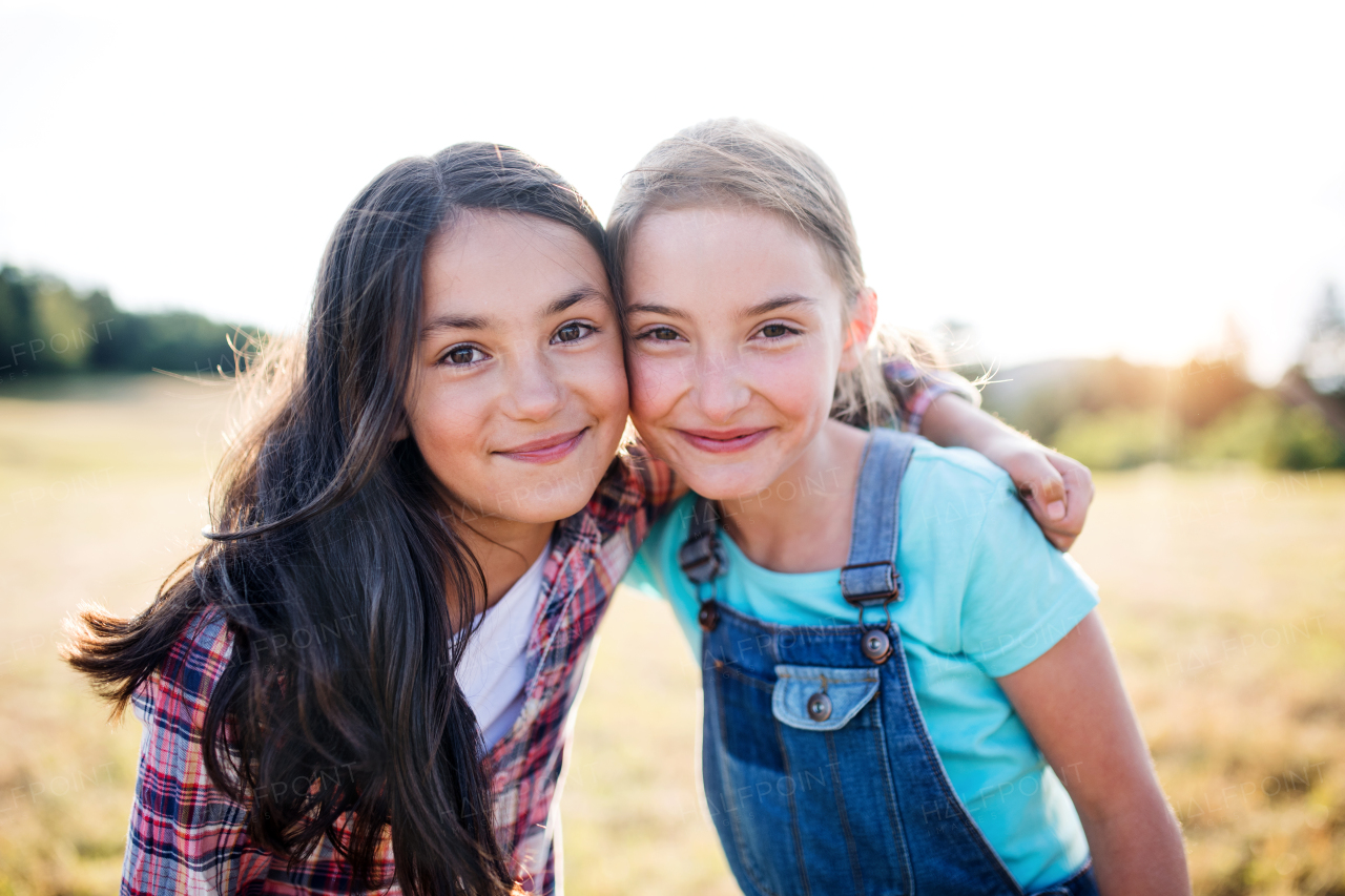 Portrait of two school children standing on field trip in nature, looking at camera.