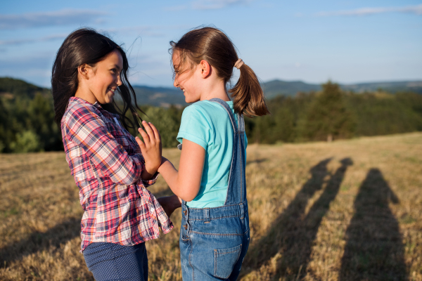 Two cheerful school children walking on field trip in nature, playing.