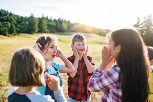 Portrait of group of school children standing on field trip in nature, playing.