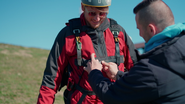 A man helping paragliding pilot to prepare for flight.