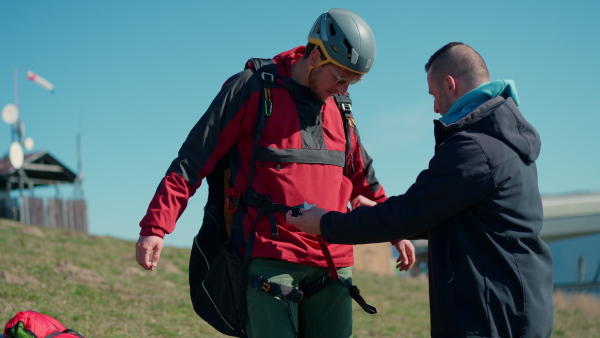 A man helping paragliding pilot to prepare for flight.