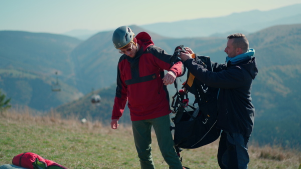 A man helping paragliding pilot to prepare for flight.