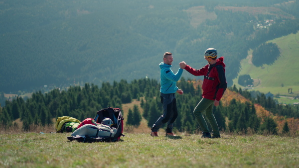 A paraglider is preparing for flight, putting on helmet.