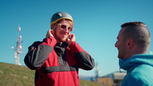 A paraglider is preparing for flight, putting on helmet.