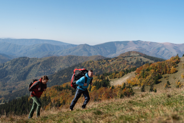 Paragliders, trekkers, mountaineers, walking up hill to a paragliding starting point, on a sunny morning in the mountains.