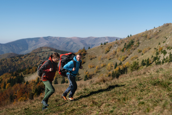 Paragliders, trekkers, mountaineers, walking up hill to a paragliding starting point, on a sunny morning in the mountains.