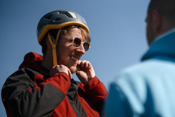 A paraglider is preparing for flight, putting on helmet.