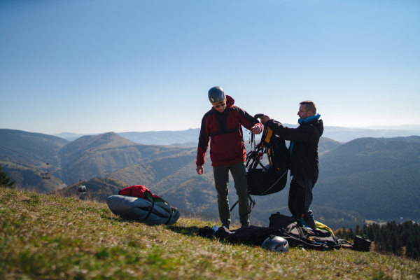 A man helping paragliding pilot to prepare for flight.