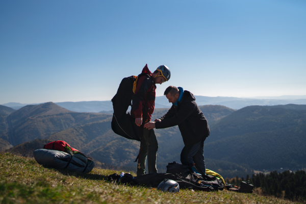 A man helping paragliding pilot to prepare for flight.