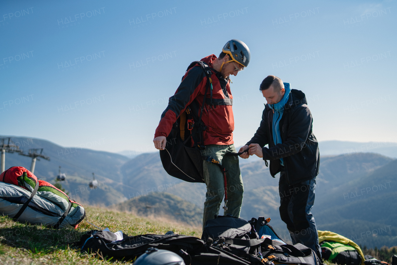 A man helping paragliding pilot to prepare for flight.