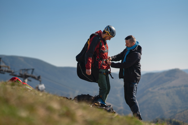 A man helping paragliding pilot to prepare for flight.