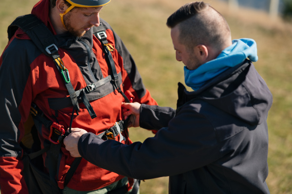 A man helping paragliding pilot to prepare for flight.