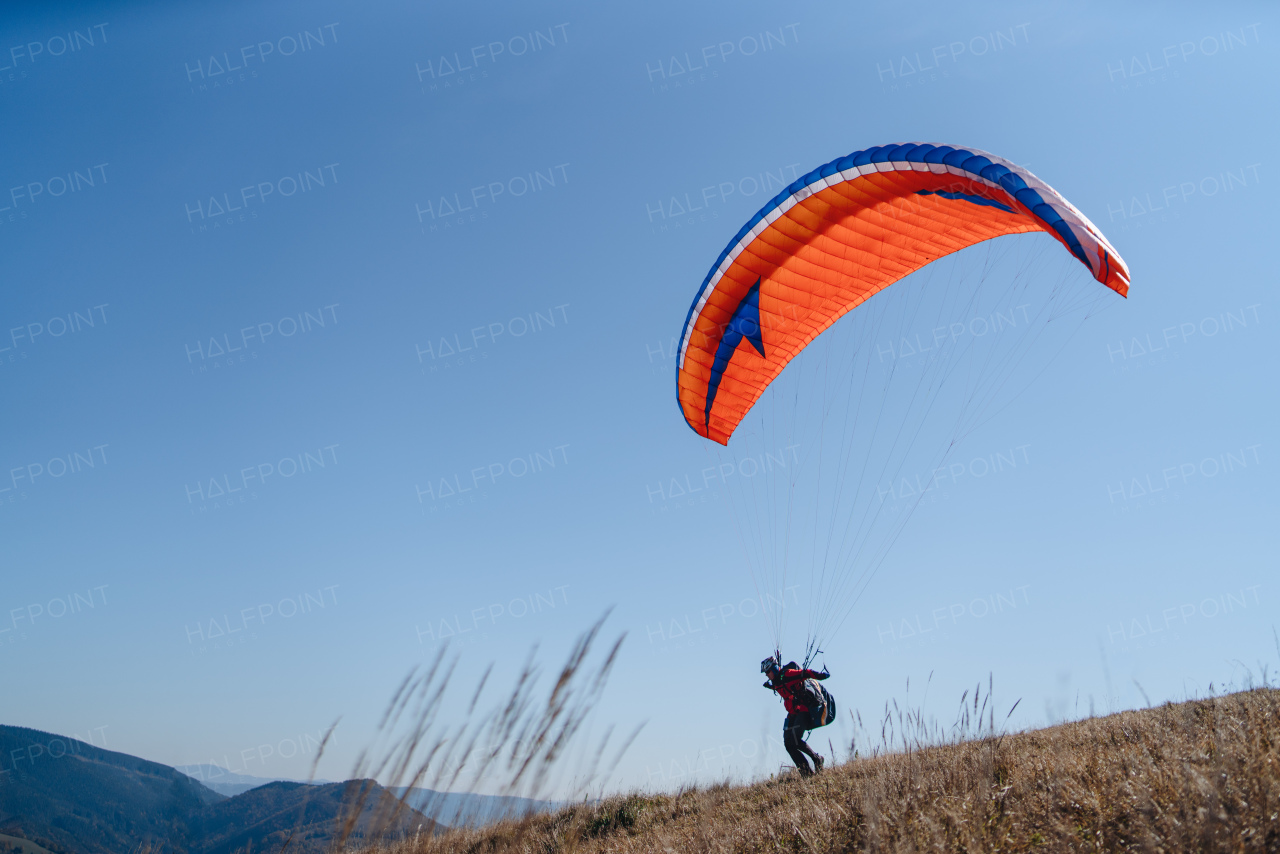 A paraglider landing on the ground against the blue sky.