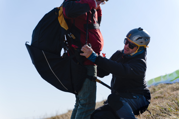 A man helping paragliding pilot to prepare for flight.