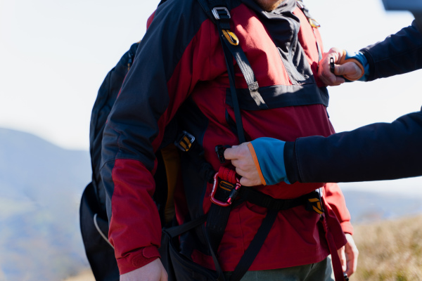 A man helping paragliding pilot to prepare for flight, close-up