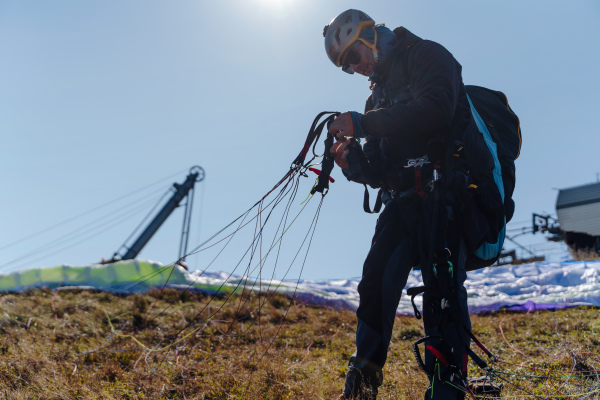 Paraglider is preparing for flight on the top of hill.