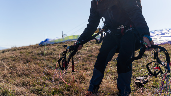 An unrecognizable paraglider is preparing for flight.