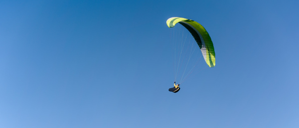 A paraglider in the blue sky. The sportsman flying on a paraglider.