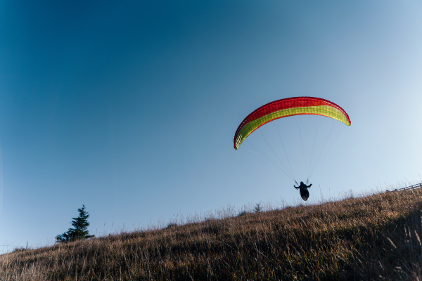 Paragliders flying in a blue sky with mountain in background.