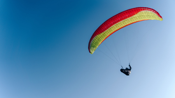 A paraglider in the blue sky. The sportsman flying on a paraglider.