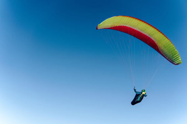 A paraglider in the blue sky. The sportsman flying on a paraglider.