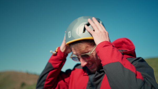 A paraglider is preparing for flight, putting on helmet.